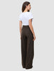 En person set bagfra, iført en hvid T-shirt og mørkebrune Serene Pants Wide Walnut Herringbone-bukser med høj talje og brede ben.
