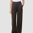 Person iført en hvid T-shirt og Serene Pants Wide Walnut Herringbone – et par højtaljede bukser med brede ben og nålestriber.