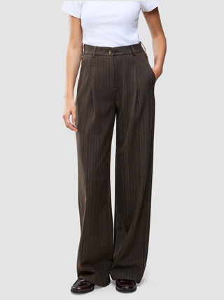 Person iført en hvid T-shirt og Serene Pants Wide Walnut Herringbone – et par højtaljede bukser med brede ben og nålestriber.