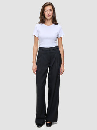 En kvinde iført en hvid T-shirt og et par Serene Pants Wide Black med brede ben.