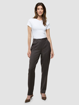 En kvinde har en hvid T-shirt med korte ærmer på, som er stoppet ned i et par Women Skye Pants Tapered Dark Chestnut Melange, samt brune højhælede sko.