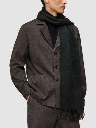 En mand iført et lidt anderledes sæt tøj: en brun Atelier Overshirt over en sort Premium Merino Knit-trøje og et tørklæde.