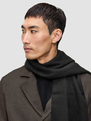 En mand bærer et anderledes jakkesæt bestående af en brun Atelier Overshirt over en sort merino-striktrøje og et mørkt tørklæde.
