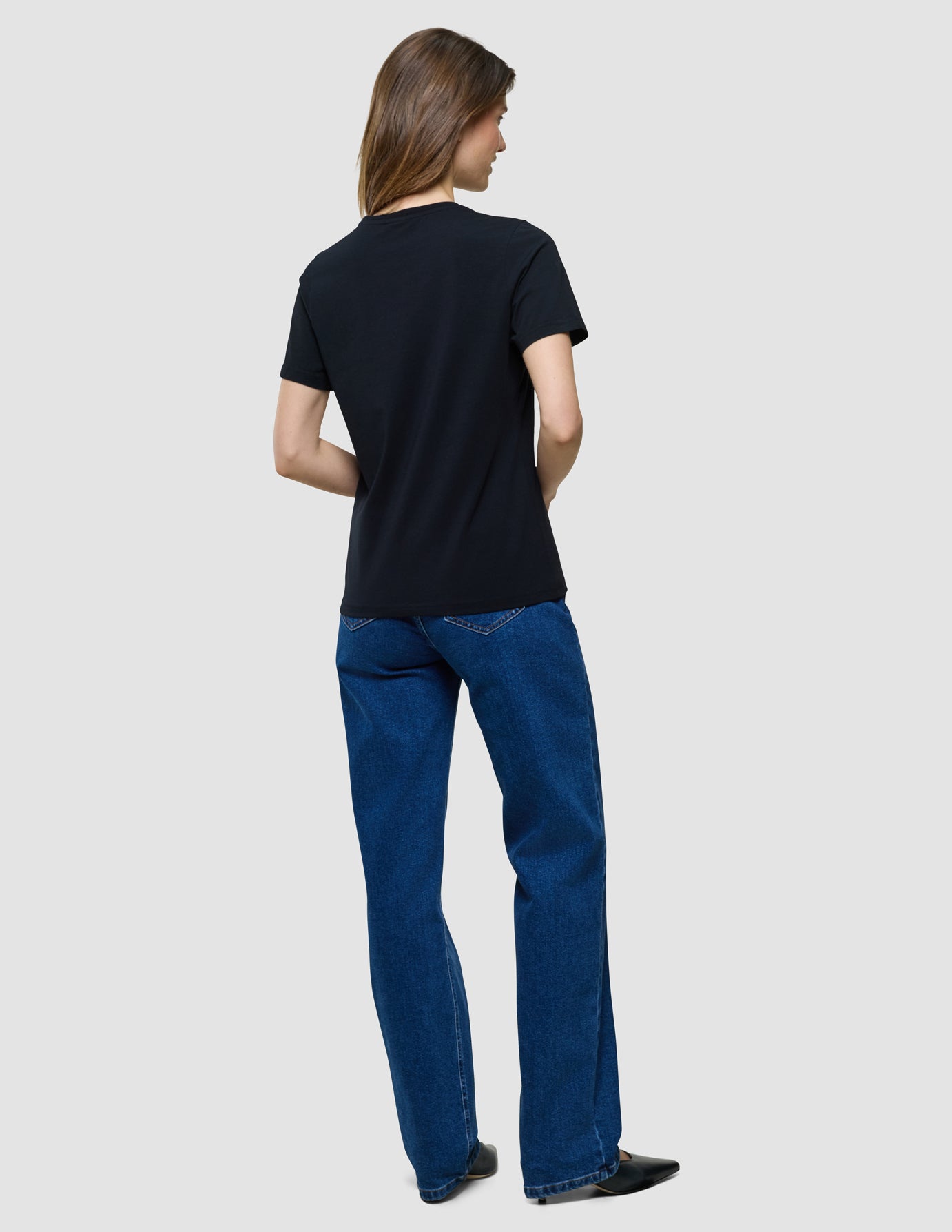 Supima T-Shirt i Black, helfigur bagfra af kvinde i sort t-shirt og blå jeans.