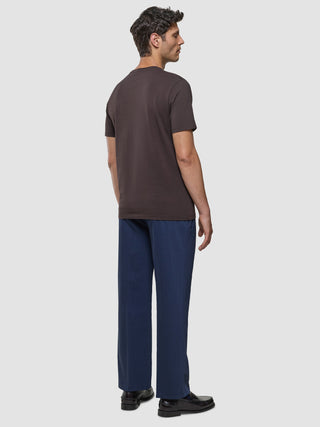 Supima T-Shirt i Deep Brown, mand set fra siden i helfigur iført brunt t-shirt og marineblå bukser.
