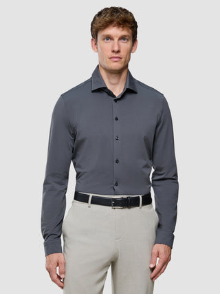 En mand i en Travel-skjorte i farven Charcoal Grey Slim, der er stukket ned i lyse bukser med et sort bælte.