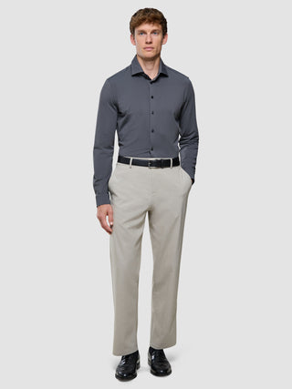 En mand iført en Travel Shirt Charcoal Grey Slim, lysegrå bukser med et sort bælte og sorte sko.