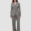 En model bærer en grå blazer i fiskebensmønster og de tilhørende Women Ashryn Pants Wide Domino Herringbone i klassisk dansk design.