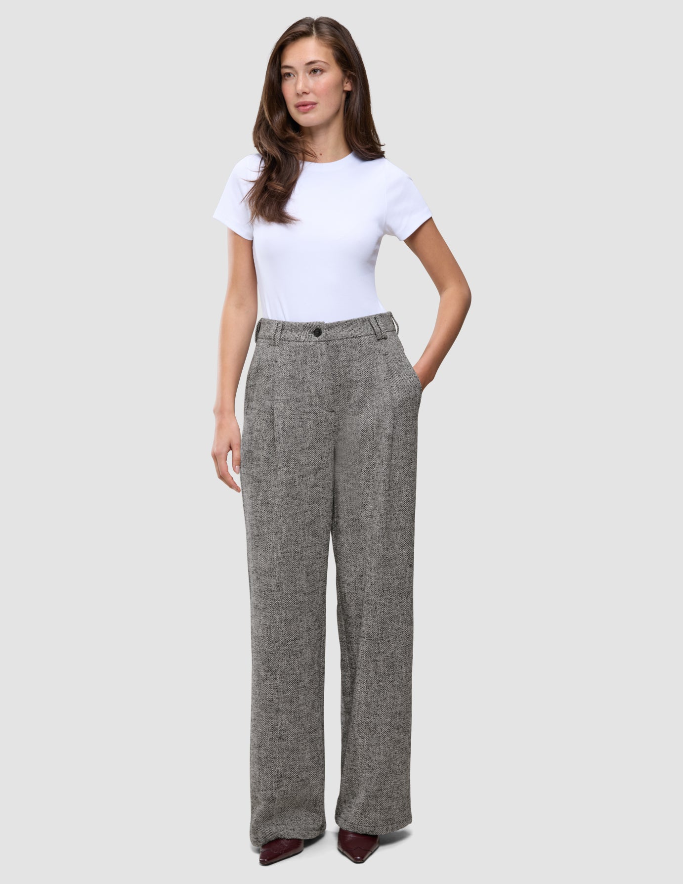 Kvinde iført en hvid T-shirt og grå Women Ashryn Pants Wide Domino Herringbone med et struktureret bouclé-mønster.