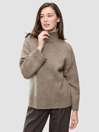 En kvinde har en Women Chunky Soft Wool Knit Turtleneck Taupe Melange på, en tyk, taupefarvet rullekravesweater i merinould.