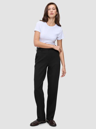 Kvinde i en hvid T-shirt, Women GO2-bukser i lige snit i sort og mørke loafers.