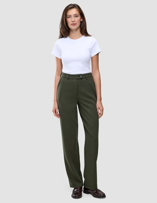 En kvinde i en hvid T-shirt, der er stukket ned i et par olivengrønne Women GO2-bukser i straight-fit i farven Dusty Olive, og mørke loafers.