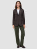 En kvinde har en brun blazer med tynde striber på over en hvid T-shirt og et par Women GO2-bukser i model Straight i farven Dusty Olive.