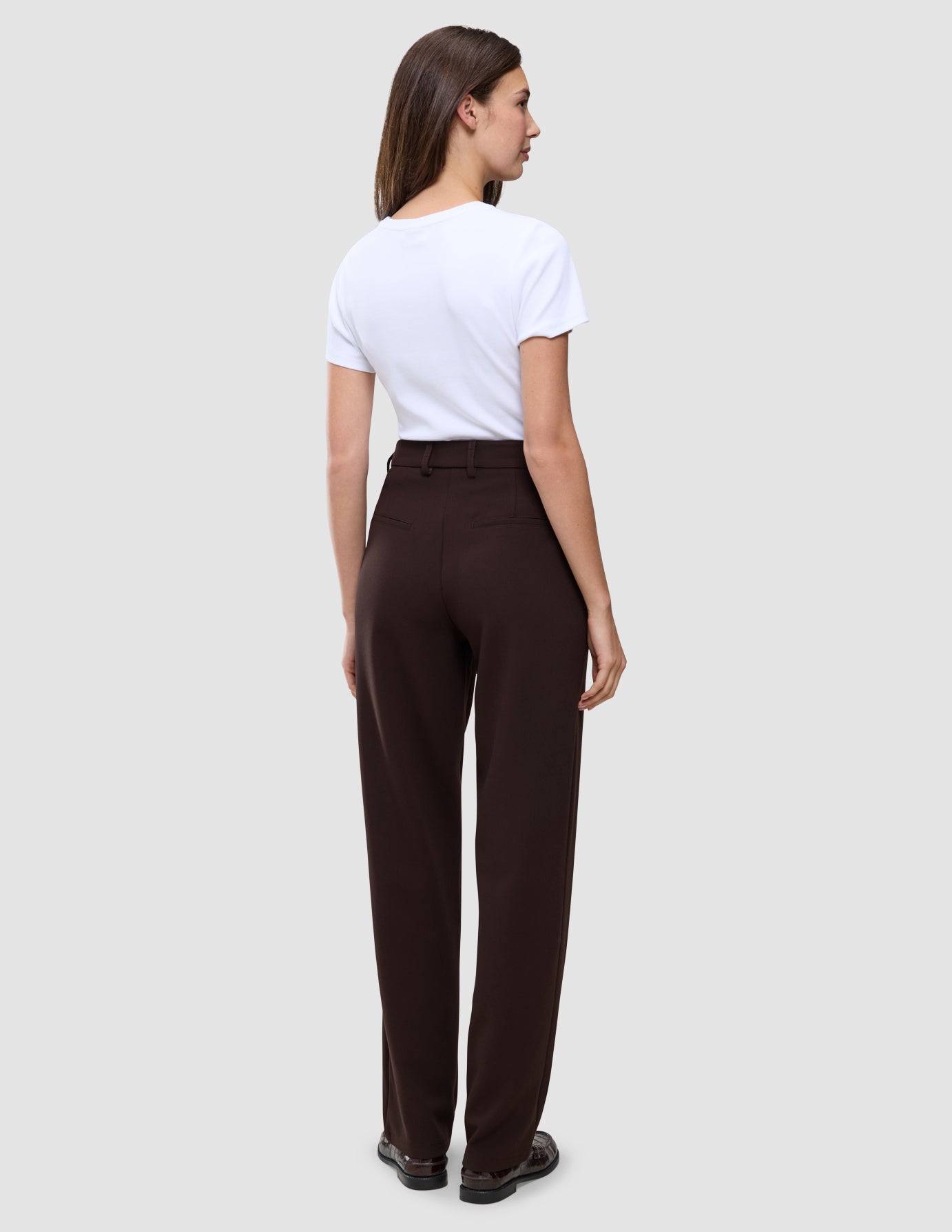 En person iført en hvid T-shirt og mørkebrune Women GO2 Pants Straight Mocha.
