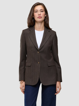 En kvinde iført en Women Serene Blazer Regular Walnut Herringbone over en hvid T-shirt og blå jeans.