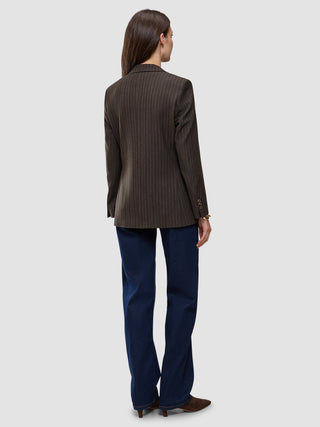 Bagfra-billede af en person iført en Women Serene Blazer Regular Walnut Herringbone, mørkeblå jeans og brune sko.