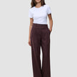En kvinde iført en hvid T-shirt og et par Women Serene Pants Wide Berry Pinstripe, som er mørkebærfarvede bukser med brede ben.