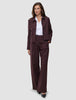 En kvinde iført et buksesæt af modellen Women Serene Pants Wide Berry Pinstripe over en hvid skjorte med krave.
