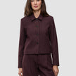 En kvinde bærer en Women Serene Short Jacket Berry Pinstripe i et mørkt bærfarvet stof med fine striber, der afspejler klassisk dansk design.