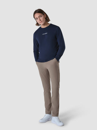 En mand iført en Supima Autograph langærmet T-shirt i farven Navy, beige bukser og hvide sneakers.