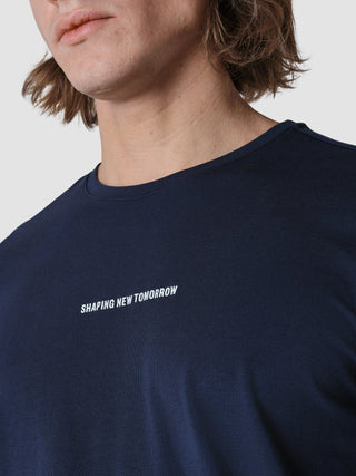 En person iført en Supima Autograph langærmet T-shirt i farven Navy med teksten »SHAPING NEW TOMORROW« trykt på brystet.