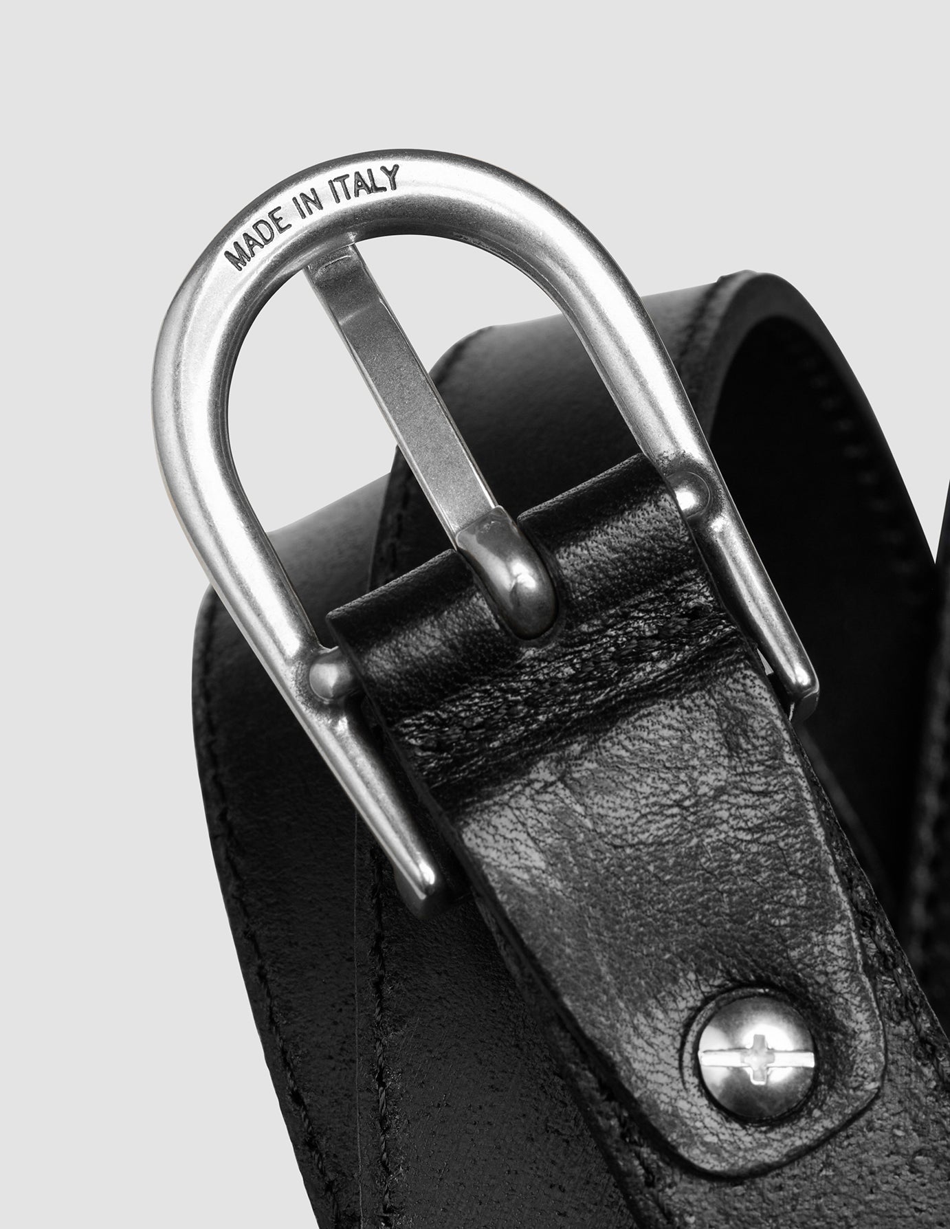 Tyndt læderbælte til kvinder i sølv og sort med en sølvspænde, hvor der er indgraveret »MADE IN ITALY«.