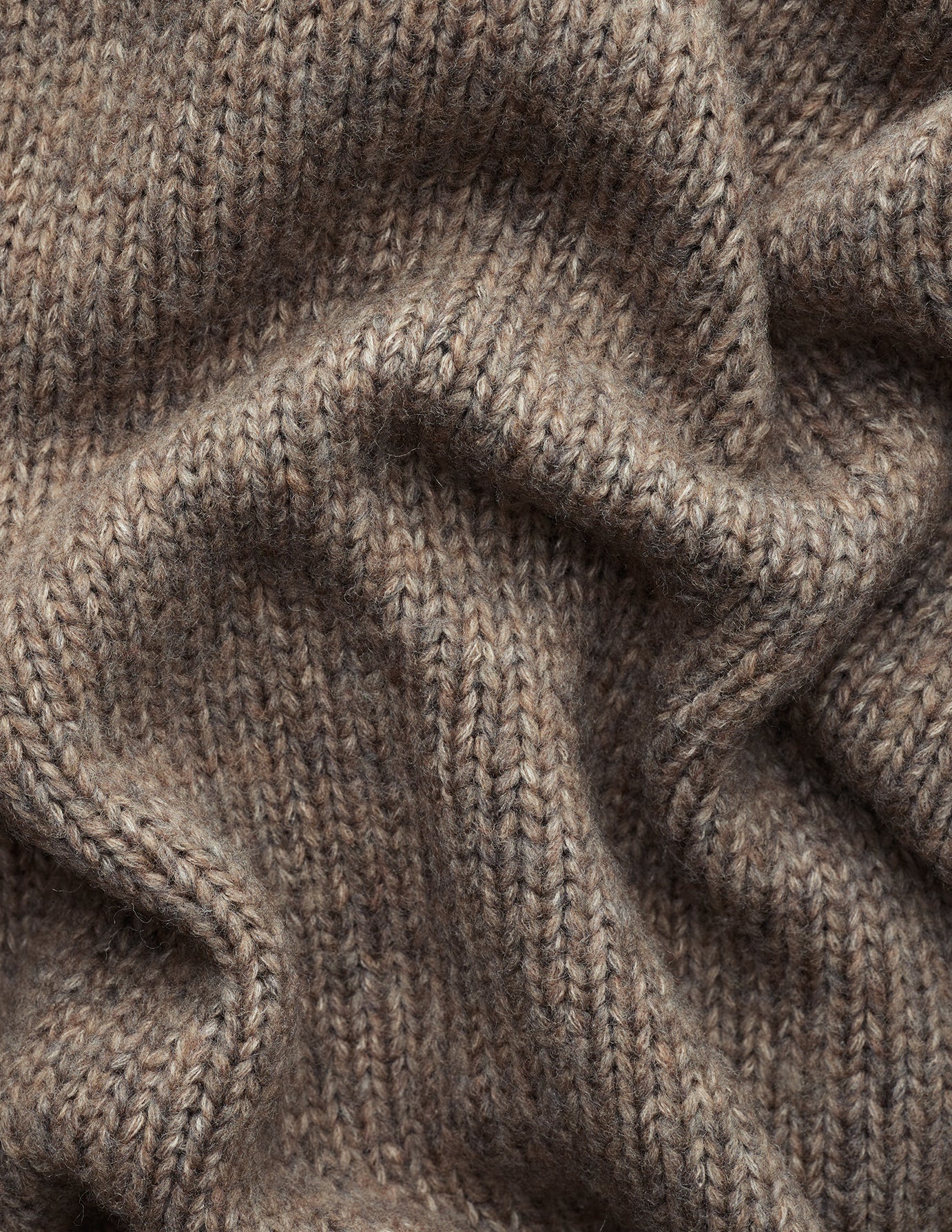 Nærbillede af et tykt, taupefarvet strikket cardigan til kvinder i blødt uld i farven Taupe Melange med bløde folder.