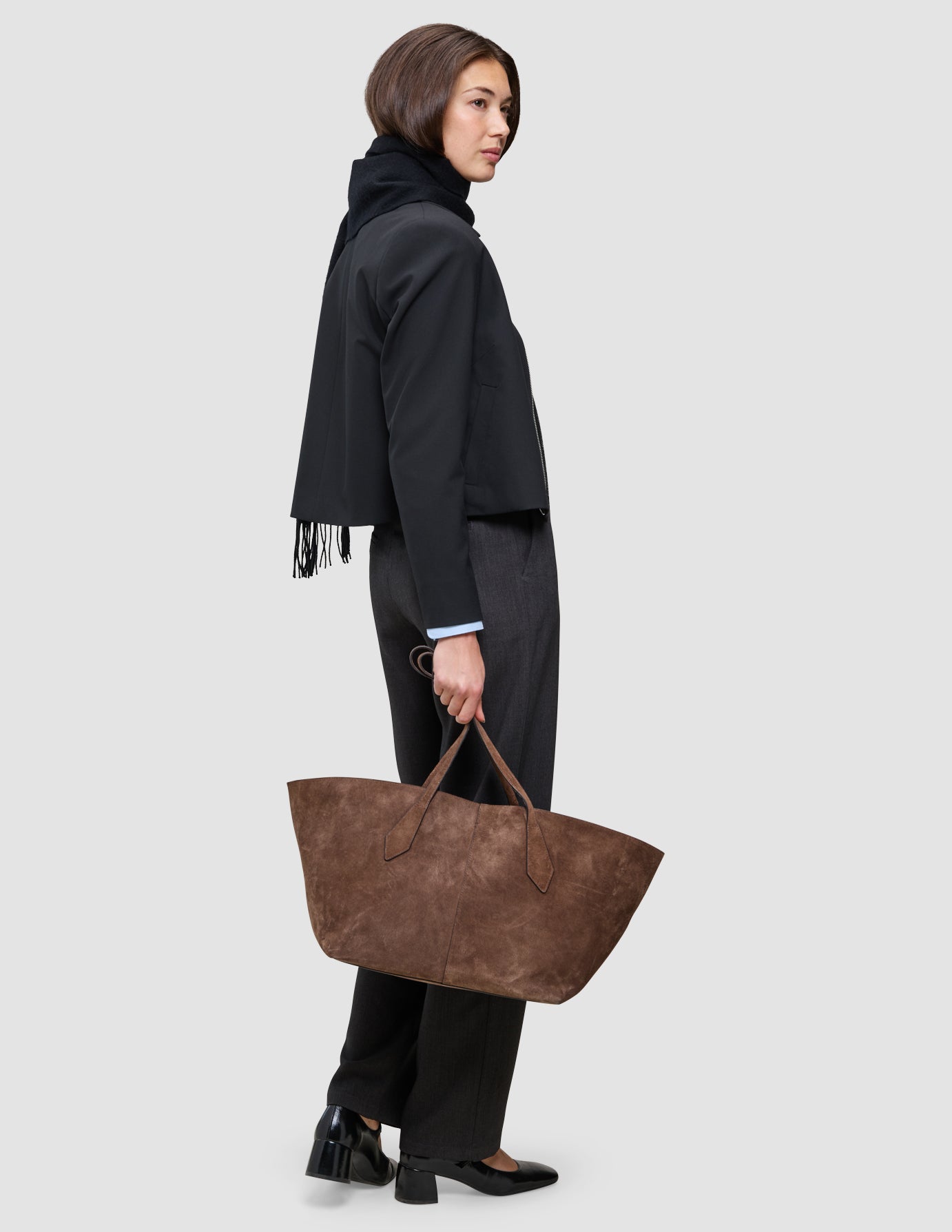 En nem opgradering af kontorlooket: En person iført en Essential Zip Jacket og Go2 Pants bærer en stor brun lædertaske.