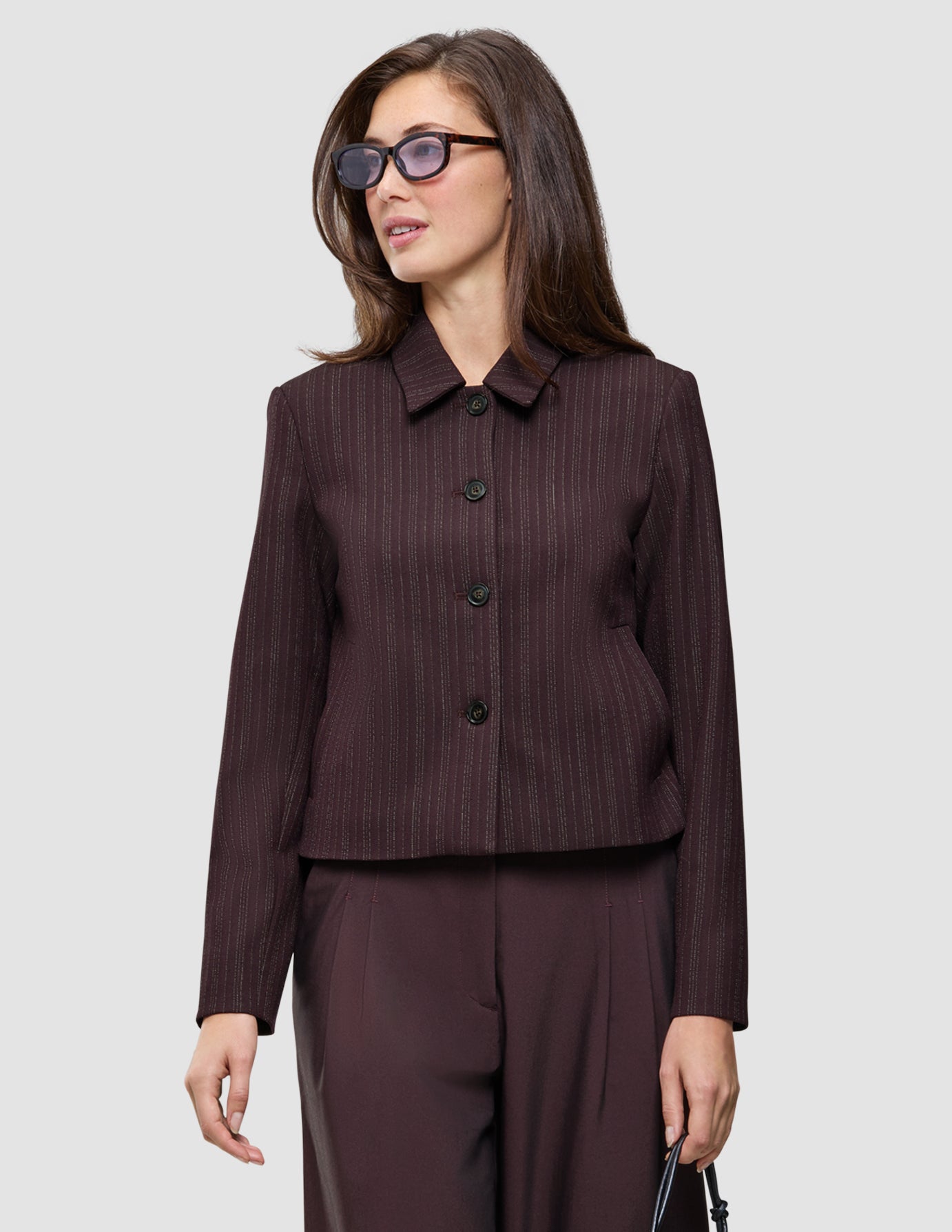 En kvinde er klædt i en Serene Short Jacket i farven Burgundy Berry fra top til tå samt de matchende Avira-bukser.