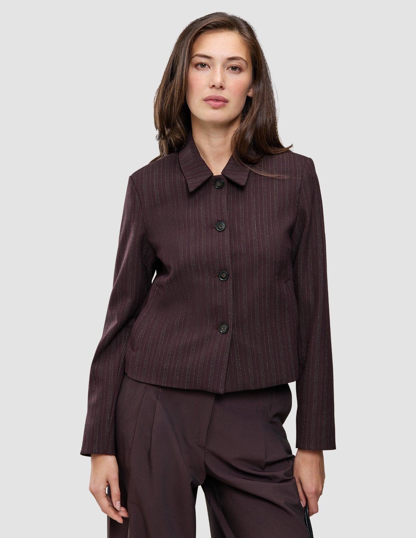 En kvinde iført en Serene Short Jacket i farven Burgundy fra top til tå og matchende Avira-bukser.