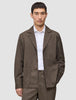 En mand iført en brun Atelier Overshirt Dark Beige over en hvid skjorte med knapper.