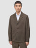 En mand har en brun Atelier Overshirt Dark Beige med udskåret krave og to påsatte lommer på over en hvid skjorte med krave.