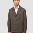 En mand har en brun Atelier Overshirt Dark Beige med udskåret krave og to påsatte lommer på over en hvid skjorte med krave.