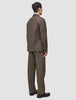 En person set bagfra, iført en Atelier Overshirt i mørk beige med matchende bukser og mørke loafers.