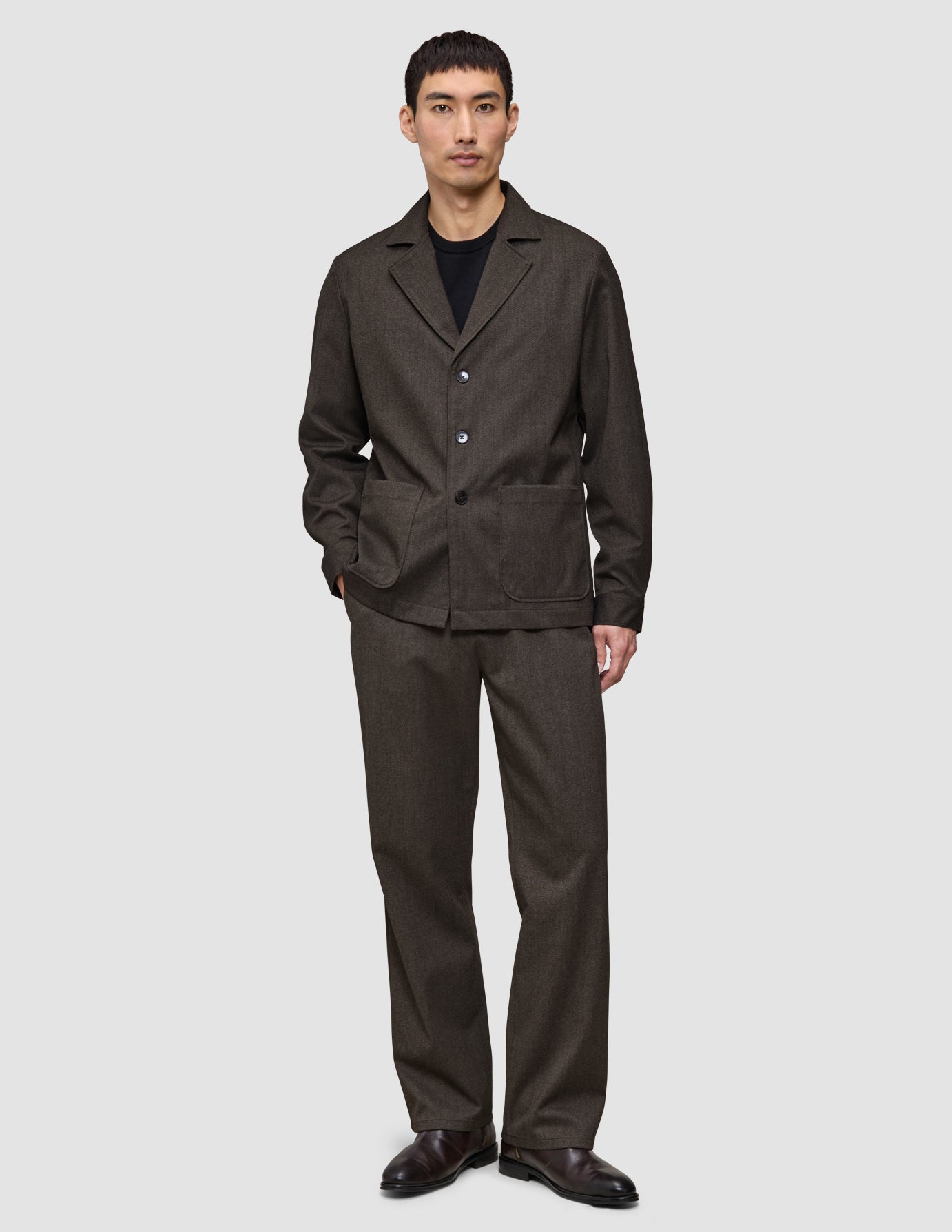 En person, der har en mørkebrun Atelier Overshirt og et par matchende bukser på.