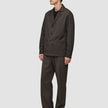 En mand iført en Atelier Overshirt i mørkebrun i et elegant dansk design med matchende bukser.