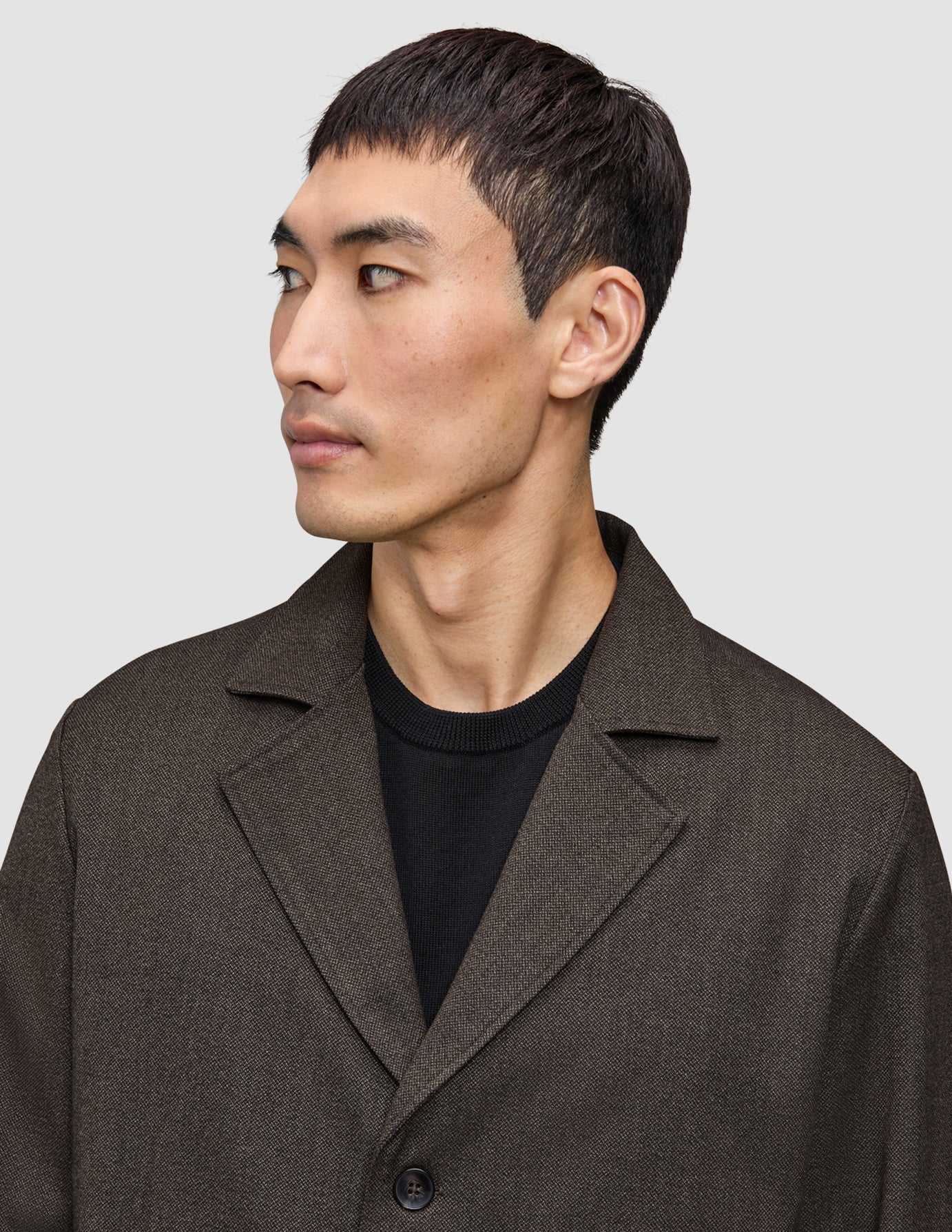 En mand, der har en mørkebrun Atelier Overshirt på over en sort sweater.