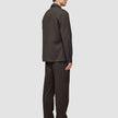 En person set fra siden, iført en mørkebrun Atelier Overshirt og matchende bukser i et rent, dansk design.