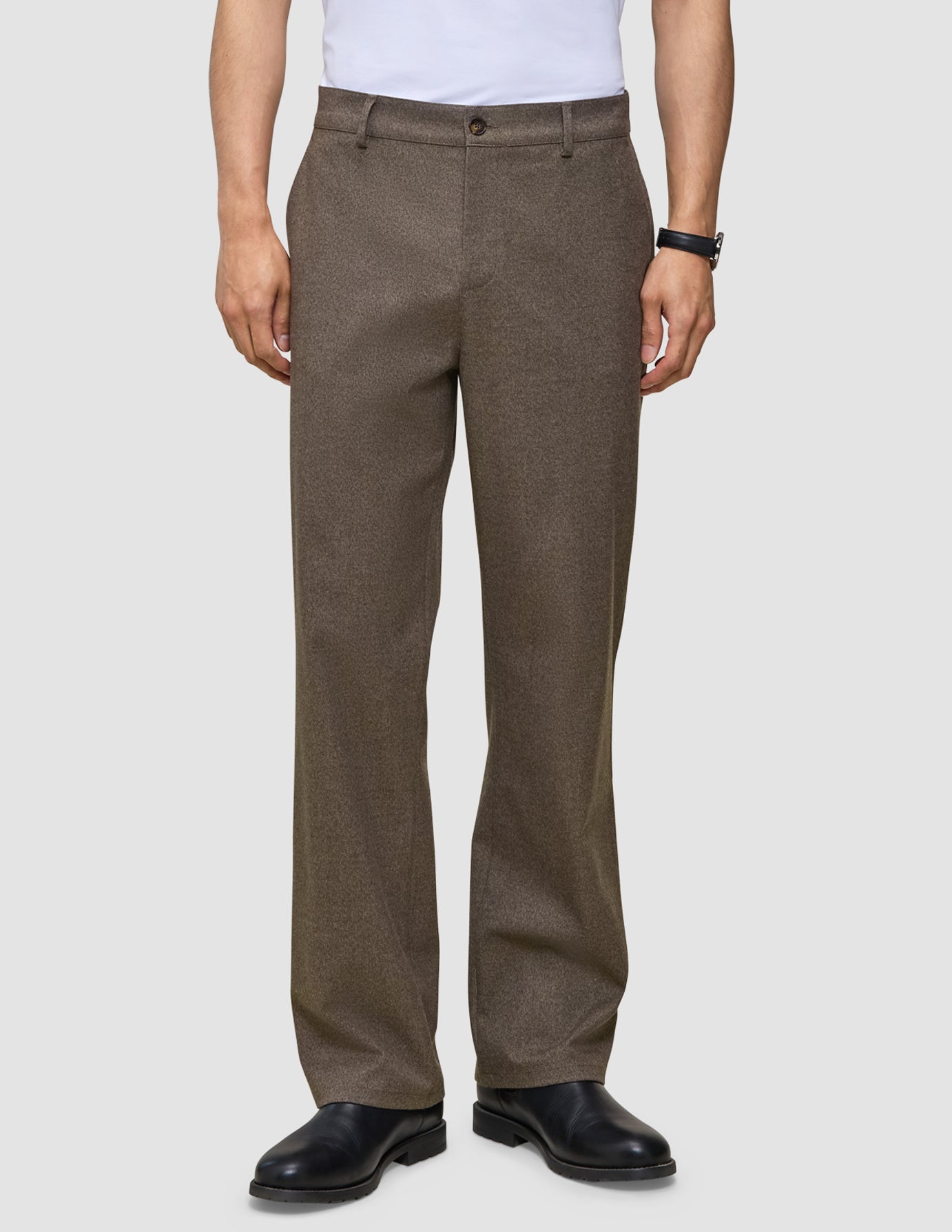 En mand iført et par Atelier Pants Relaxed Dark Beige i kraftigt, brudt twill og håndlavede sorte lædersko fra Portugal.