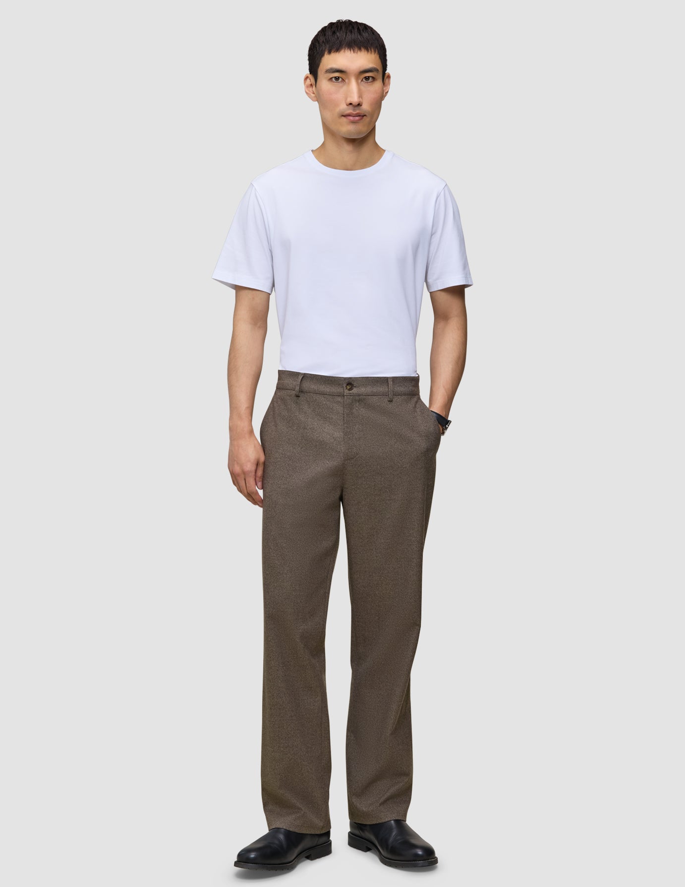 En mand i en hvid T-shirt, mørkebegige Atelier Pants Relaxed og sorte sko.