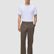 En mand i en hvid T-shirt, mørkebegige Atelier Pants Relaxed og sorte sko.