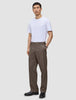 En mand har en hvid T-shirt, sorte sko og et par Atelier Pants Relaxed Dark Beige i kraftigt, brudt twill på.