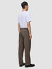 En person set bagfra, iført en hvid T-shirt og Atelier Pants Relaxed Dark Beige i kraftig, brudt twill.