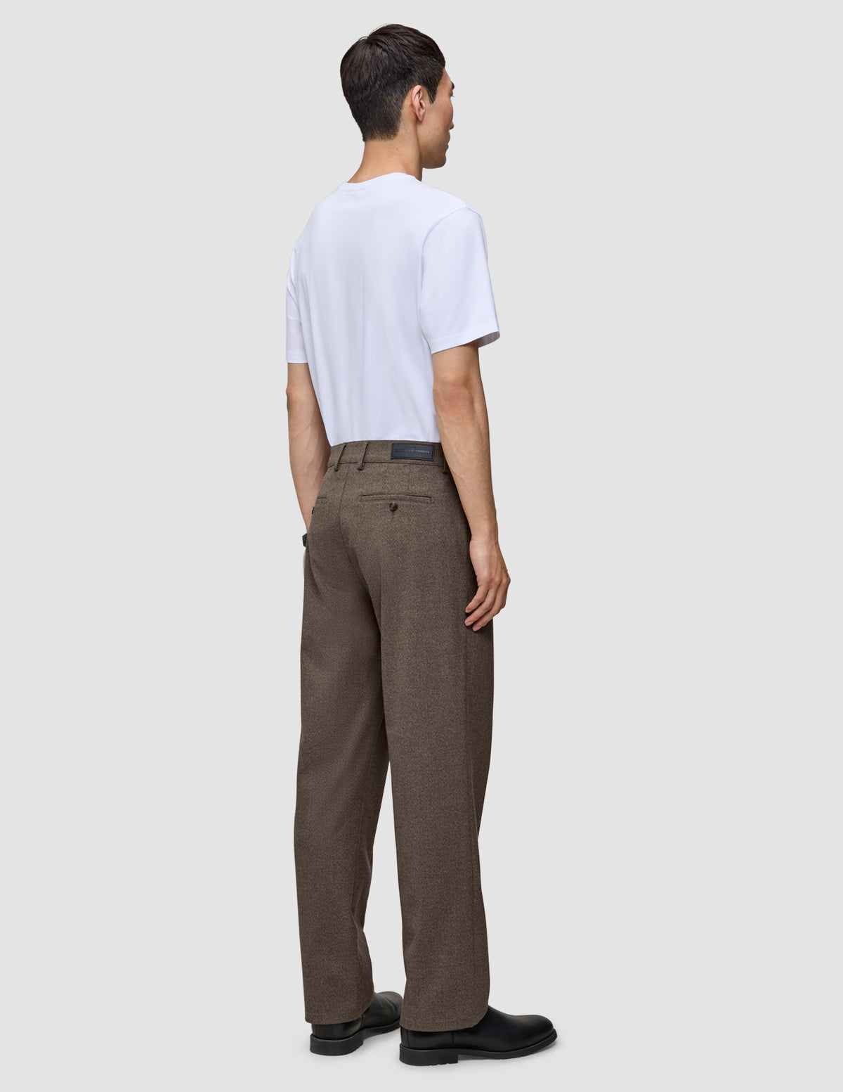 En person set bagfra, iført en hvid T-shirt og Atelier Pants Relaxed Dark Beige i kraftig, brudt twill.