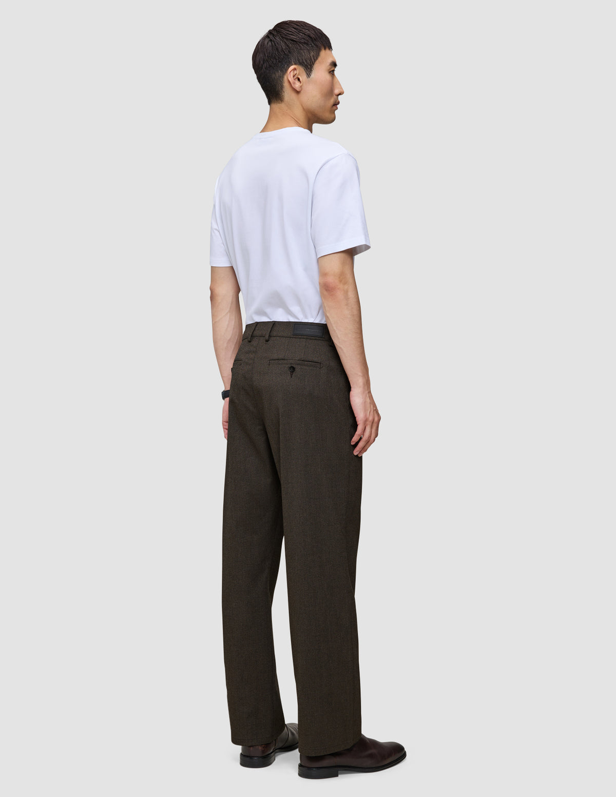 En person set bagfra, iført en hvid T-shirt og mørkebrune Atelier Pants Relaxed – et eksempel på dansk design.