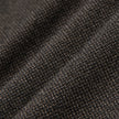 Nærbillede af de opfoldede Atelier Pants Relaxed i mørkebrun, brudt twill-stof med et struktureret, plettet væv.