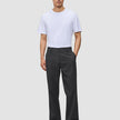 En mand har en hvid T-shirt på og mørkegrå Atelier Pants Relaxed i brudt twill.
