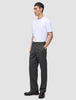 En mand iført en hvid T-shirt og et par Atelier Pants Relaxed i mørkegrå, med afslappet pasform og i et brudt twill-stof.