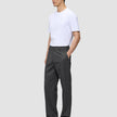 En mand iført en hvid T-shirt og et par Atelier Pants Relaxed i mørkegrå, med afslappet pasform og i et brudt twill-stof.