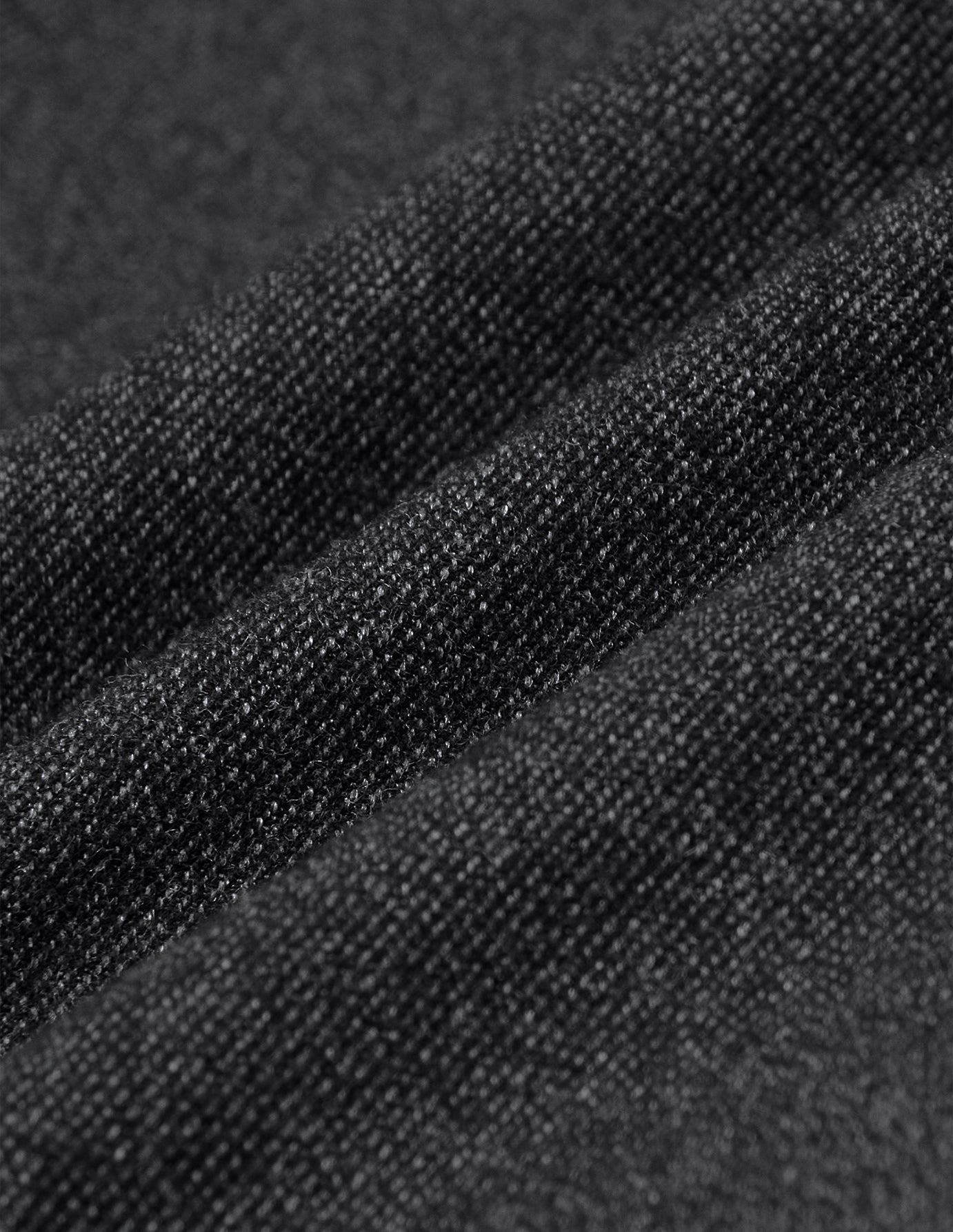 Nærbillede af Atelier Pants Relaxed Dark Grey i et mørkegråt stof med brudt twill-vævning og en struktureret, strikagtig overflade.